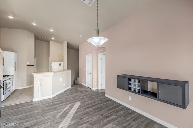 kitchen with pendant lighting, white appliances, hardwood / wood-style floors, white cabinets, and a kitchen island