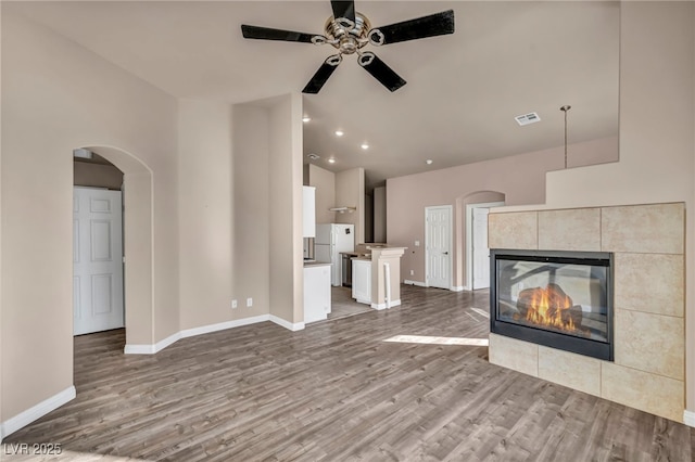 unfurnished living room with hardwood / wood-style flooring, a fireplace, ceiling fan, and vaulted ceiling