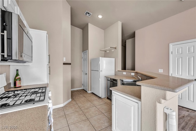 kitchen featuring sink, light tile patterned floors, kitchen peninsula, white appliances, and white cabinets