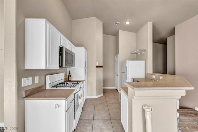 kitchen with light tile patterned floors, white appliances, and white cabinets