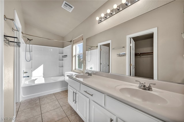 bathroom featuring tile patterned flooring, tiled shower / bath, lofted ceiling, and vanity