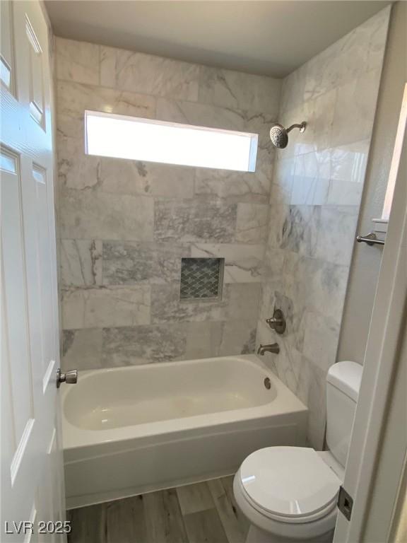 bathroom featuring hardwood / wood-style flooring, toilet, and tiled shower / bath combo