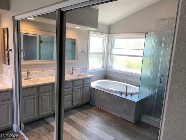 bathroom with vanity, vaulted ceiling, separate shower and tub, and hardwood / wood-style flooring