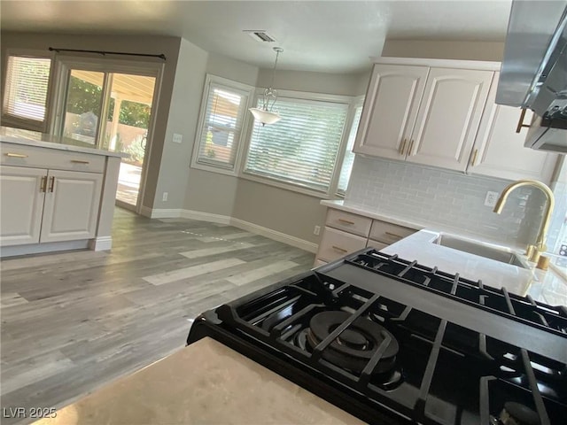 kitchen with white cabinets, decorative light fixtures, a wealth of natural light, and sink