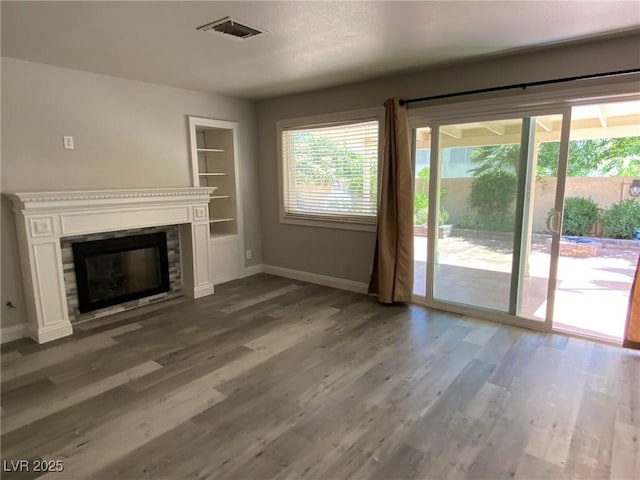 unfurnished living room with hardwood / wood-style floors and built in features