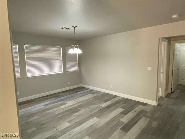 unfurnished room featuring a chandelier and dark hardwood / wood-style flooring