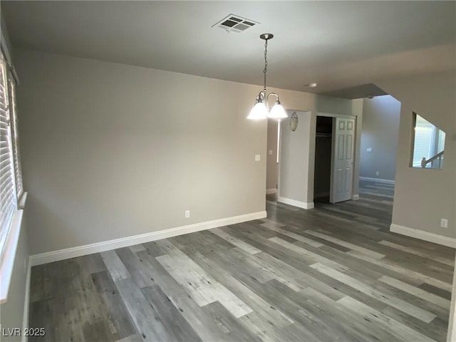 unfurnished dining area featuring an inviting chandelier and dark wood-type flooring