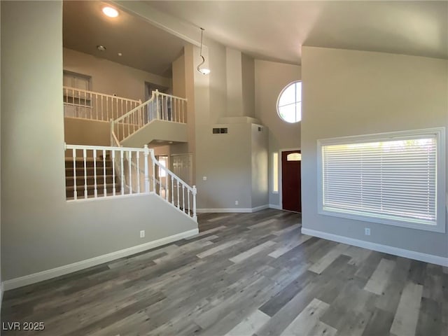 unfurnished living room featuring a towering ceiling and dark hardwood / wood-style floors