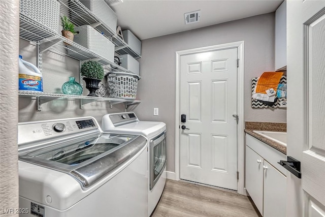 laundry room featuring light hardwood / wood-style floors, cabinets, and independent washer and dryer