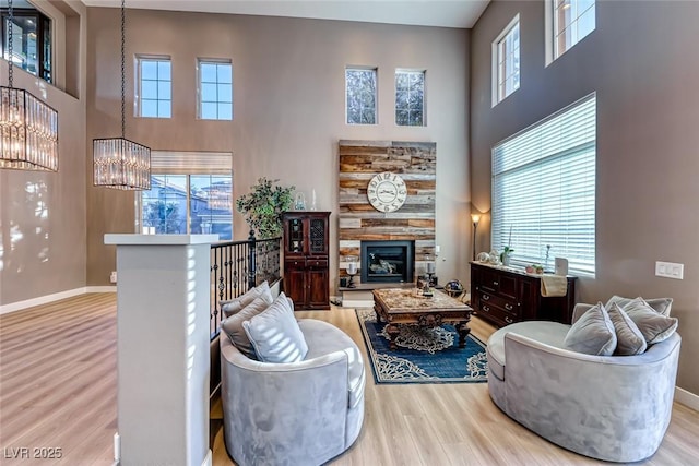 living room featuring a towering ceiling, light hardwood / wood-style flooring, and an inviting chandelier