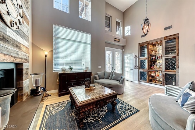 living room featuring light hardwood / wood-style floors, a high ceiling, and french doors