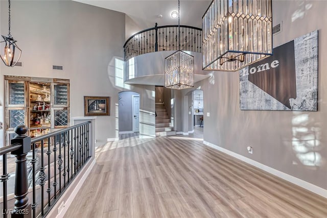 entryway featuring a notable chandelier, a towering ceiling, and hardwood / wood-style flooring