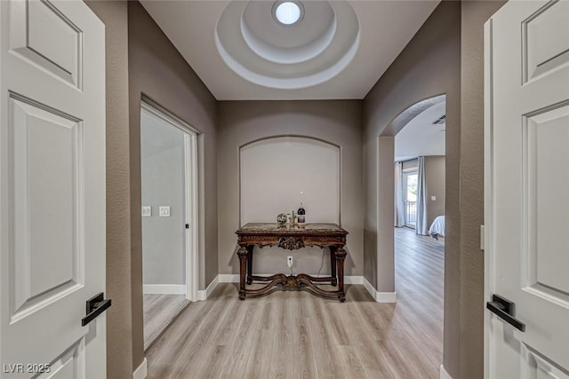 hall featuring a tray ceiling and light hardwood / wood-style flooring