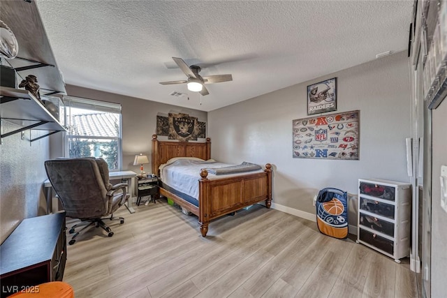 bedroom with ceiling fan, light hardwood / wood-style flooring, and a textured ceiling