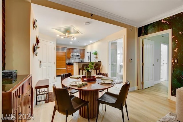 dining room with ornamental molding and light hardwood / wood-style floors