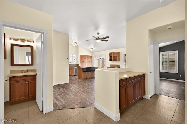 kitchen with dishwasher, ceiling fan, sink, light tile patterned floors, and lofted ceiling