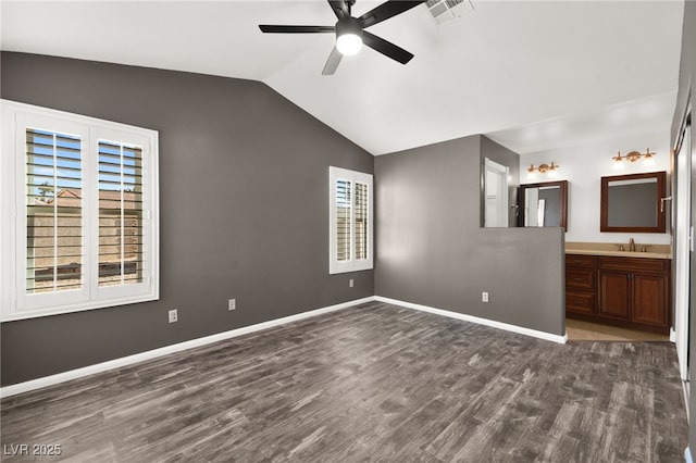 unfurnished bedroom featuring ensuite bathroom, sink, dark wood-type flooring, ceiling fan, and lofted ceiling