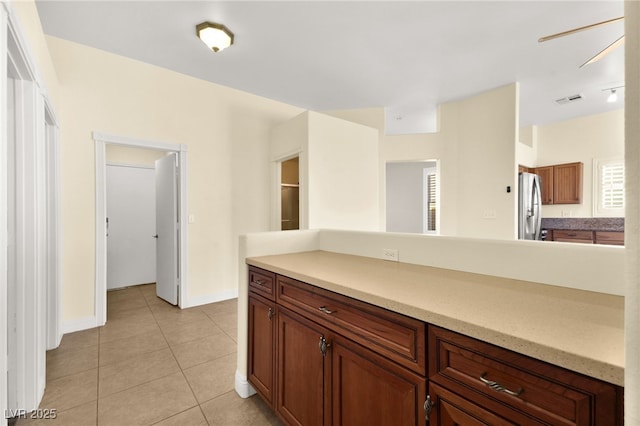 kitchen featuring ceiling fan, stainless steel refrigerator, and light tile patterned flooring