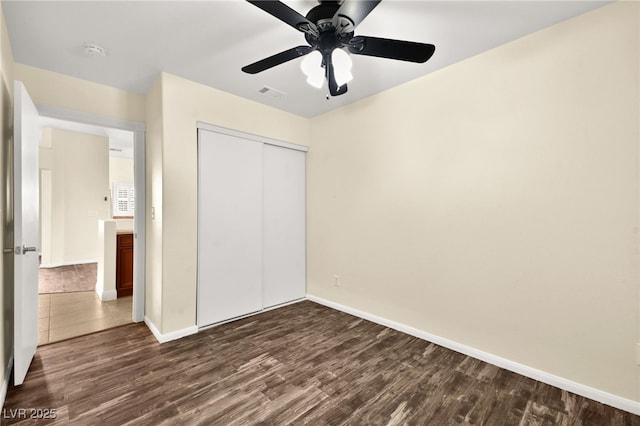 unfurnished bedroom featuring a closet, ceiling fan, and dark wood-type flooring