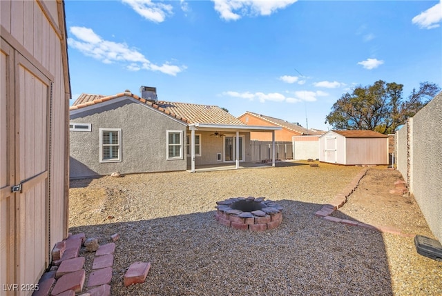 rear view of house with a storage unit, ceiling fan, an outdoor fire pit, and a patio area