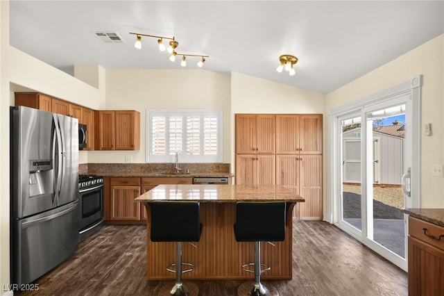 kitchen featuring dark wood-type flooring, appliances with stainless steel finishes, sink, and a kitchen island