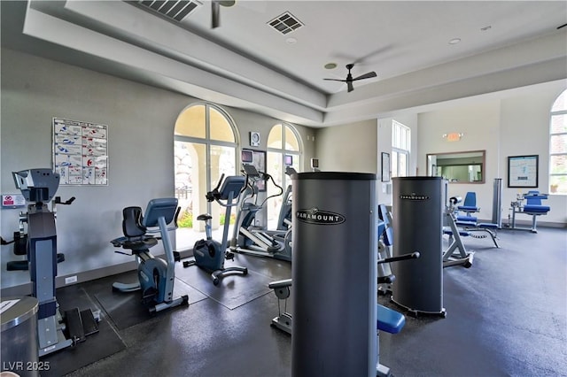 gym with a raised ceiling and ceiling fan