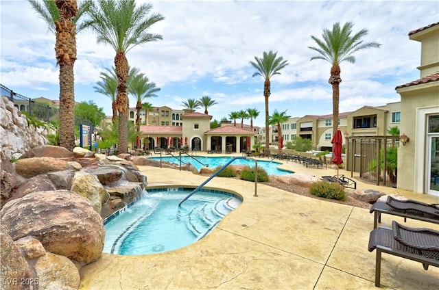 view of swimming pool with pool water feature, a hot tub, and a patio