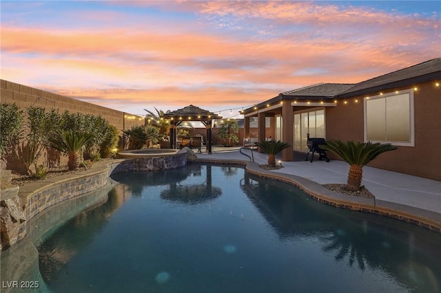 pool at dusk with an in ground hot tub, a gazebo, and a patio