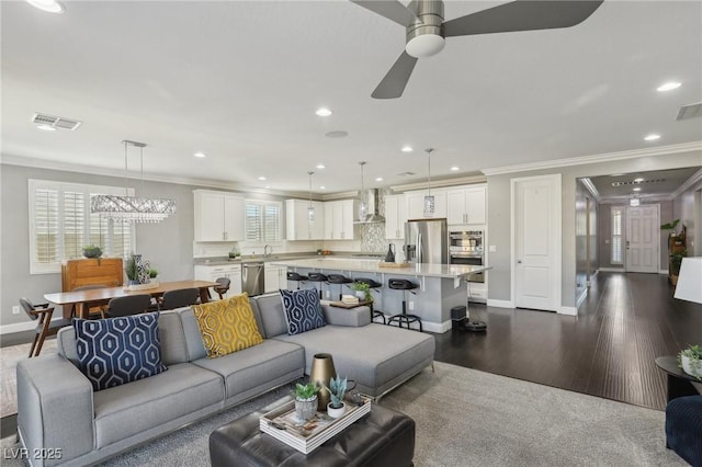 living room featuring sink, ceiling fan, ornamental molding, and dark wood-type flooring