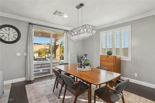 dining space featuring a chandelier, ornamental molding, and dark hardwood / wood-style flooring