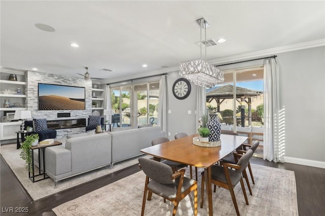 dining area with built in features, a healthy amount of sunlight, ornamental molding, and dark wood-type flooring