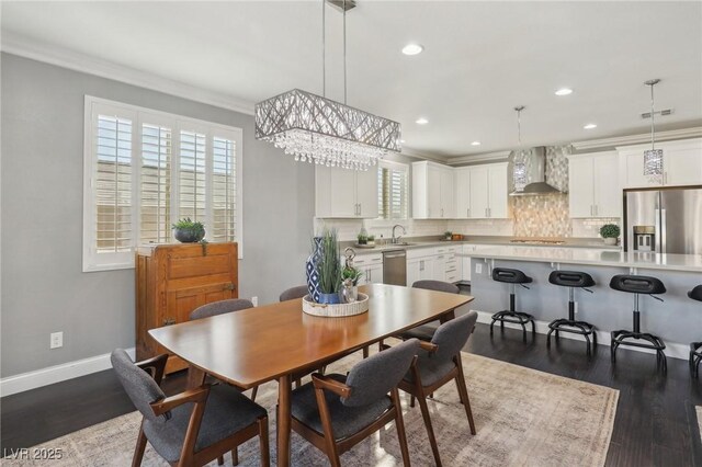 dining space featuring sink, ornamental molding, and dark wood-type flooring