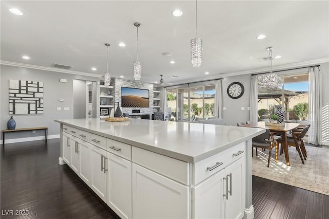 kitchen with white cabinets, built in shelves, a wealth of natural light, and decorative light fixtures