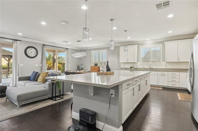 kitchen with white cabinets, a center island, pendant lighting, and tasteful backsplash