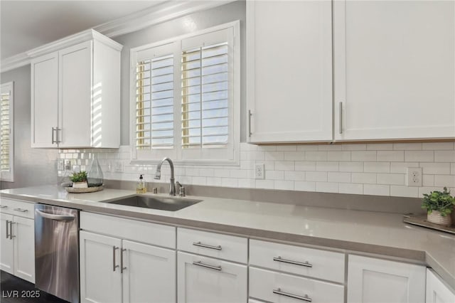 kitchen featuring tasteful backsplash, dishwasher, sink, white cabinets, and ornamental molding