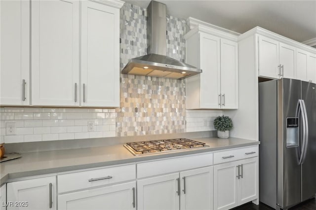 kitchen with wall chimney exhaust hood, white cabinets, tasteful backsplash, and stainless steel appliances