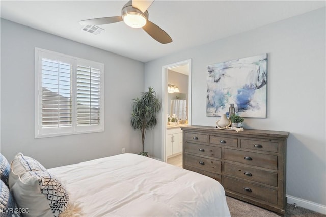 bedroom featuring ceiling fan, light colored carpet, and ensuite bath