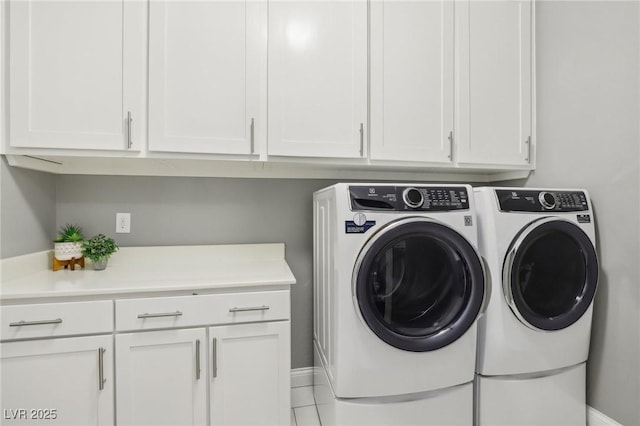 laundry area with cabinets, washing machine and dryer, and light tile patterned floors