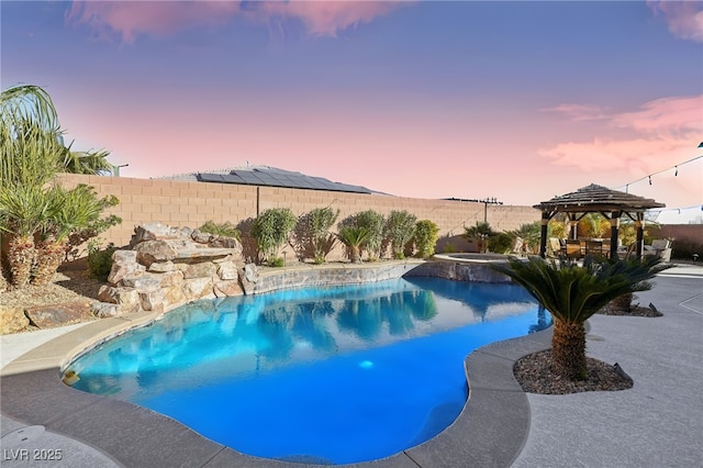 pool at dusk with an in ground hot tub and a gazebo