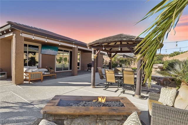 patio terrace at dusk featuring an outdoor fire pit and a gazebo