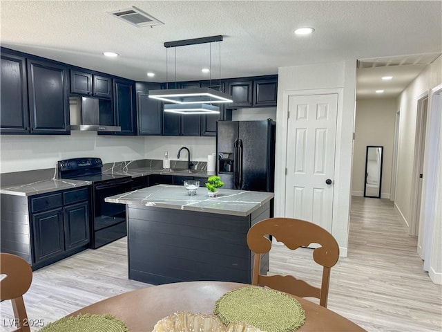 kitchen featuring light hardwood / wood-style flooring, decorative light fixtures, a textured ceiling, a kitchen island, and black appliances