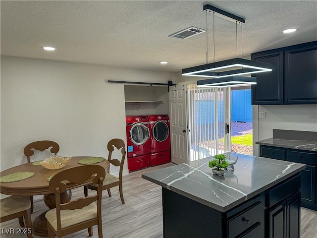 kitchen featuring a textured ceiling, a barn door, a kitchen island, pendant lighting, and independent washer and dryer