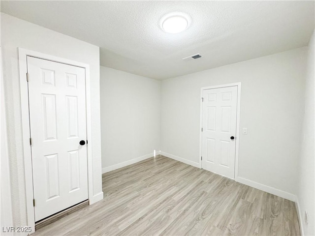 unfurnished room with light hardwood / wood-style floors and a textured ceiling