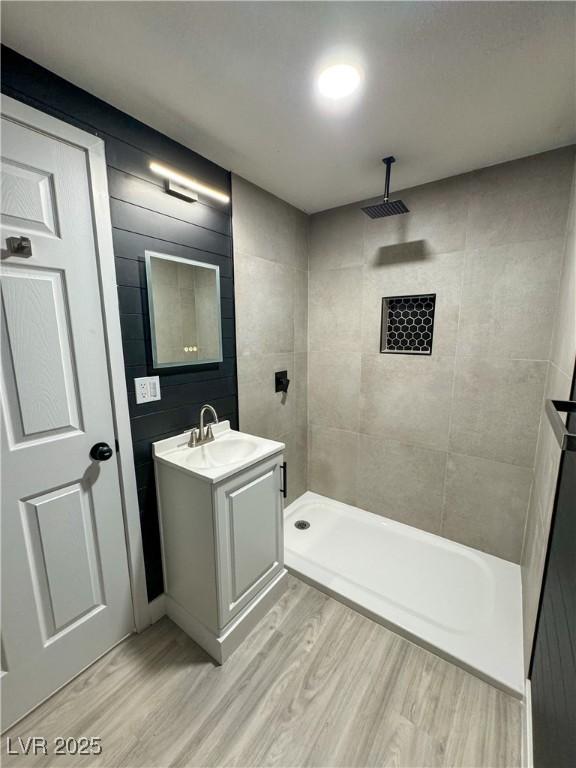 bathroom with vanity, tiled shower, and hardwood / wood-style floors