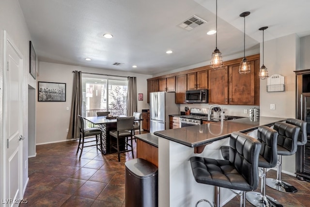 kitchen with stainless steel appliances, kitchen peninsula, a kitchen breakfast bar, and decorative light fixtures