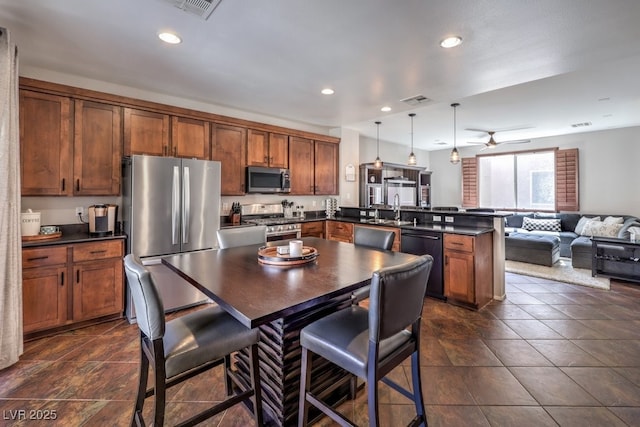 kitchen with a center island, stainless steel appliances, hanging light fixtures, kitchen peninsula, and a breakfast bar