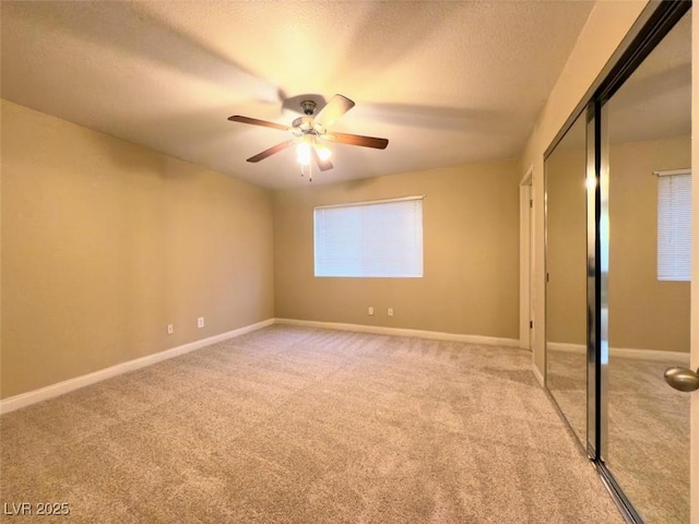 unfurnished bedroom with ceiling fan, a textured ceiling, a closet, and light carpet