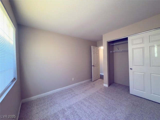 unfurnished bedroom featuring light carpet and a closet