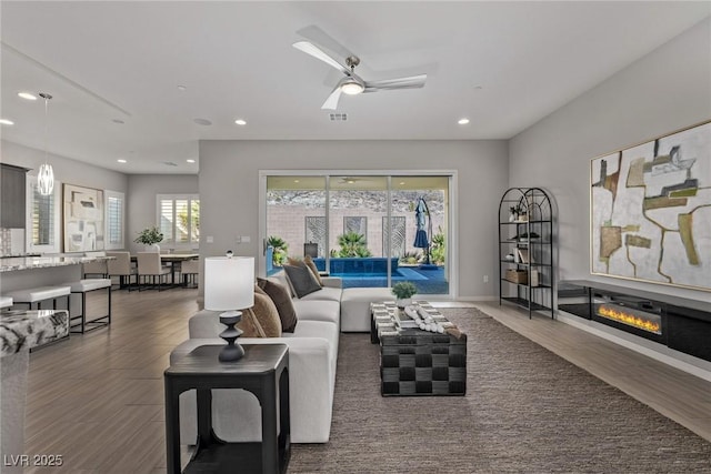 living room featuring recessed lighting, visible vents, wood finished floors, and a glass covered fireplace