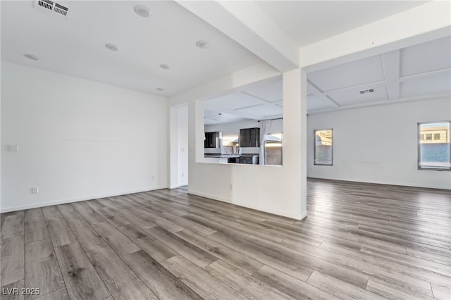 unfurnished living room with coffered ceiling, beam ceiling, and light hardwood / wood-style flooring